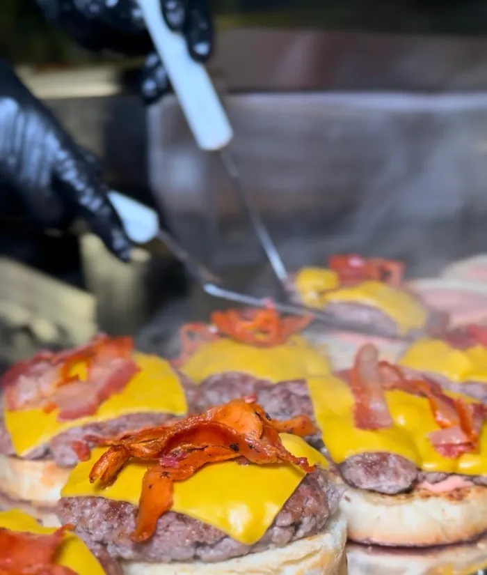 Medallones con cheddar y tocino en la plancha durante un servicio.